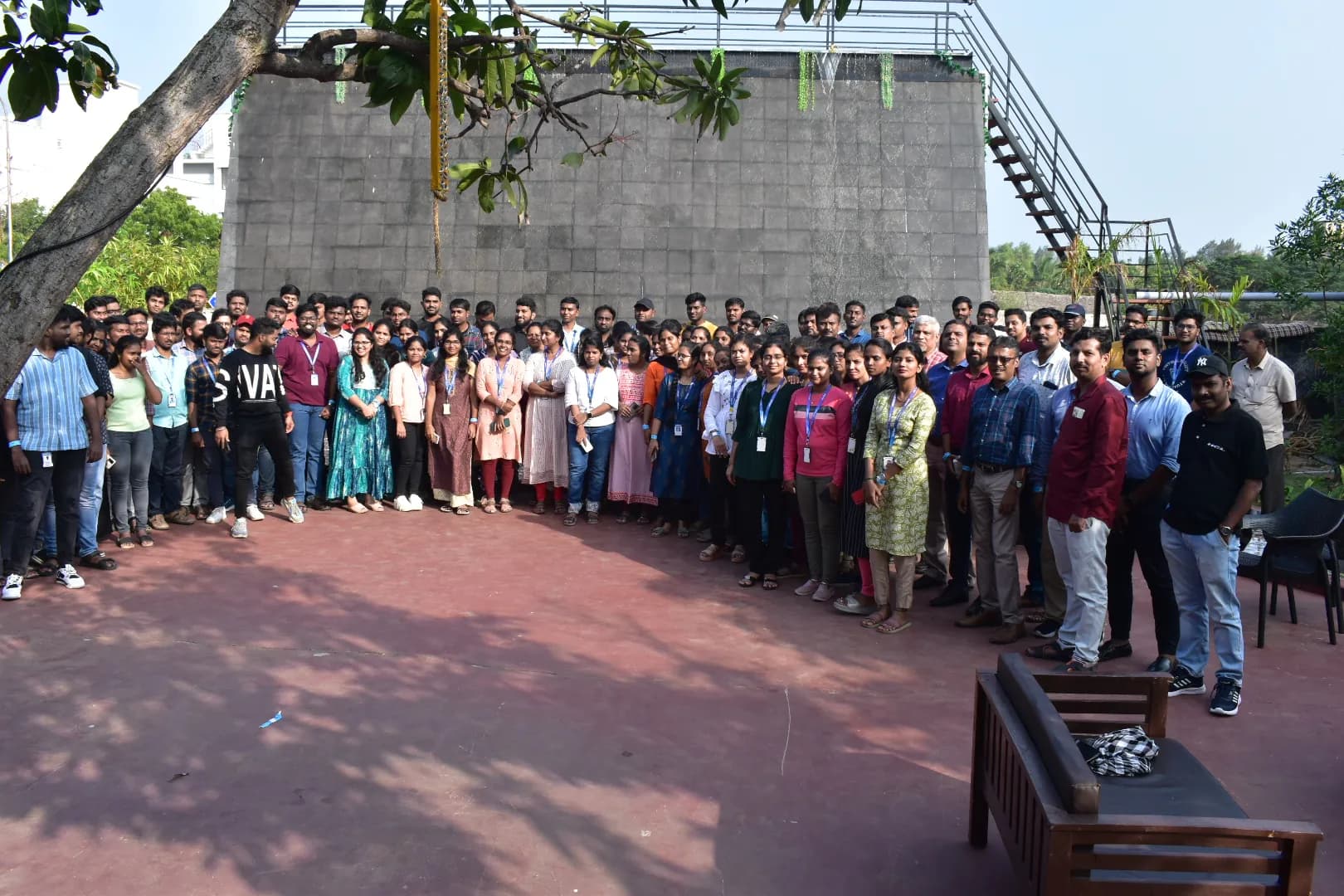 A large corporate group seated outdoors under trees at Aruvi Restaurant